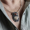 Necklace with a pendant featuring two stones worn by a person.