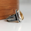 Silver ring with textured band on a wooden surface