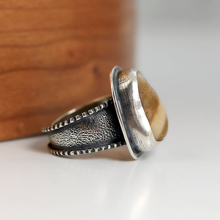 Silver ring with textured band on a wooden surface
