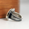 Silver ring with textured design on a wooden surface