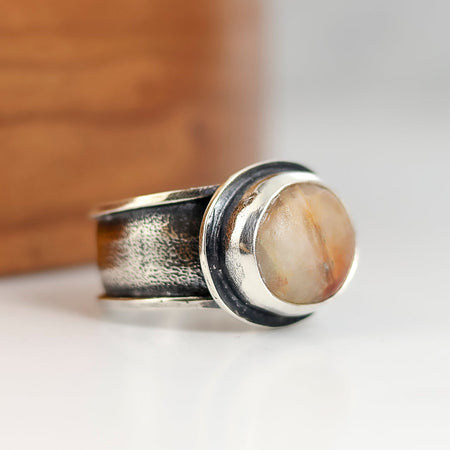 Silver ring with a beach stone  on a wooden surface