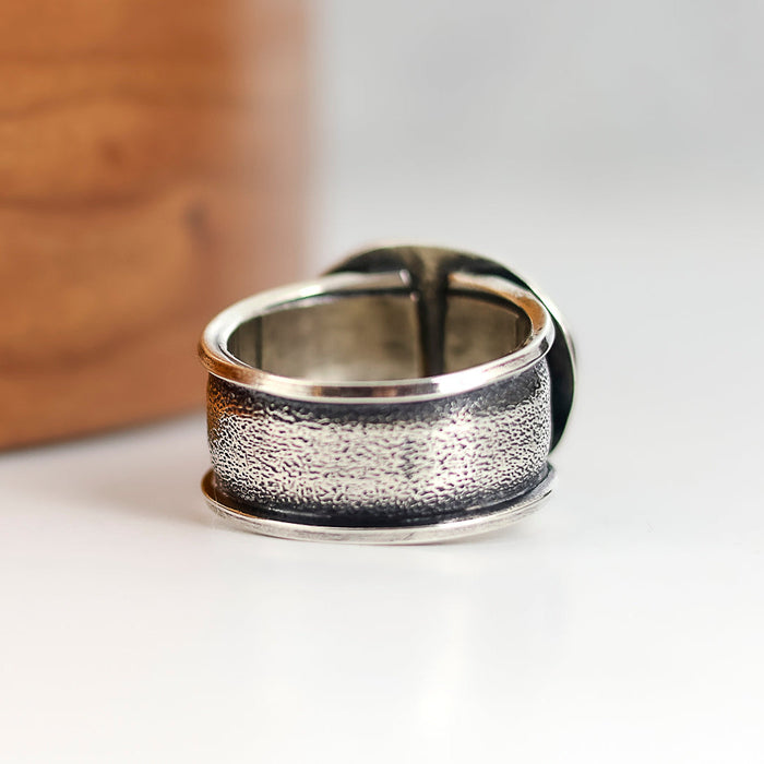 Silver ring with textured design on a white surface