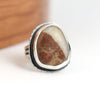 Silver ring with a large stone on a white surface