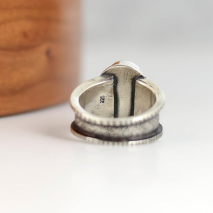 Silver ring with textured design on a white surface
