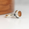 Silver ring with a brown stone on a light background