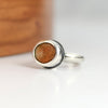 Silver ring with a brown stone on a white surface