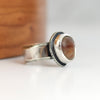 Silver ring with a brown stone on a white surface