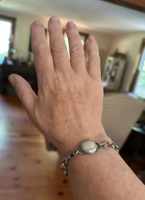 Hand wearing a silver bracelet with a beach stone setting