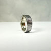 Silver ring with textured band on a white surface
