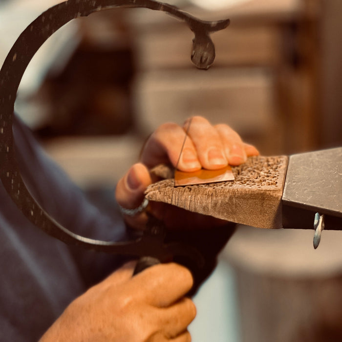Person using a metal file on a piece of wood with a blurred background