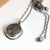 Necklace with a pendant featuring a dark beach stone on a white background