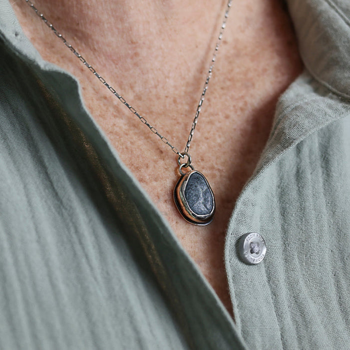 Necklace with a pendant worn by a person wearing a light green shirt.