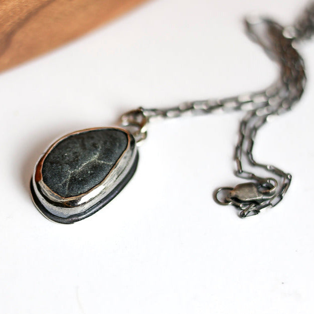 Necklace with a  beach stone pendant on a white surface
