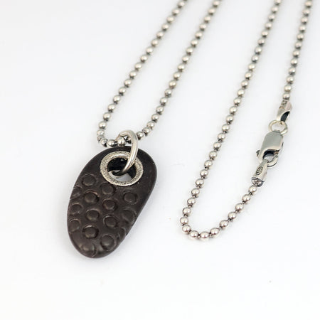 beach stone pendant on a silver chain on a white background