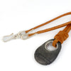 A dark gray stone pendant with a silver grommet threaded onto a tan leather cord with silver clasp, shown on a white background.