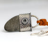 beach stone pendant with a silver textured end cap on a brown suede cord