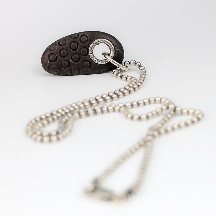 beach stone pendant on a silver chain on a white background