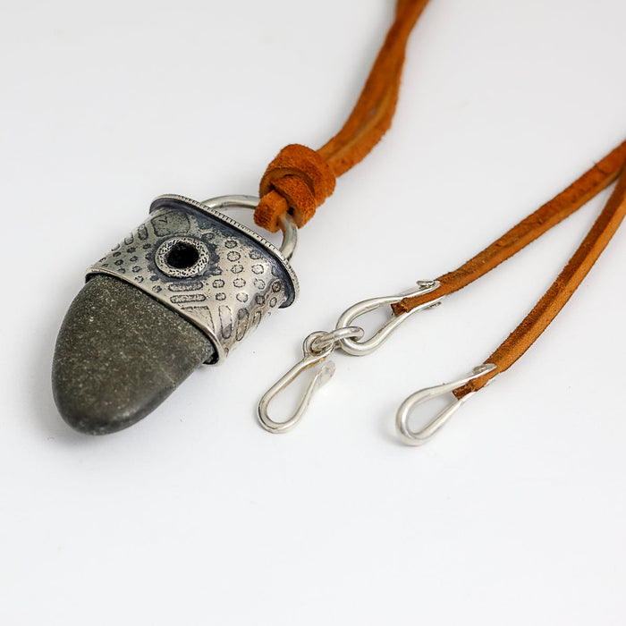 beach stone pendant with a silver textured end cap on a brown suede cord