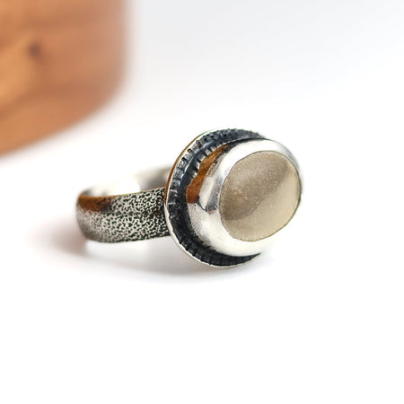 Silver ring with textured band on a white background