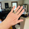 Hand wearing a ring with a beach  stone in a room setting
