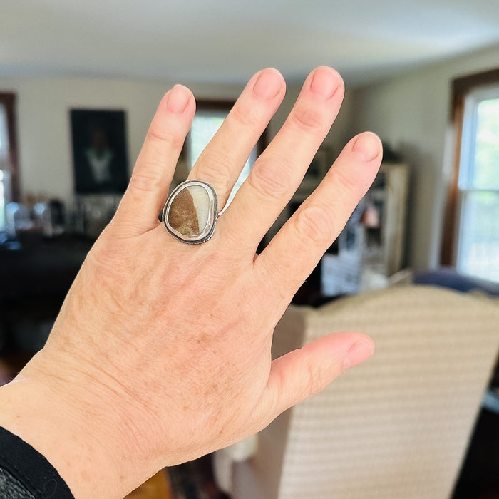 Hand wearing a large ring with a blurred indoor background
