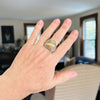 Hand wearing a ring with a stone on a blurred indoor background