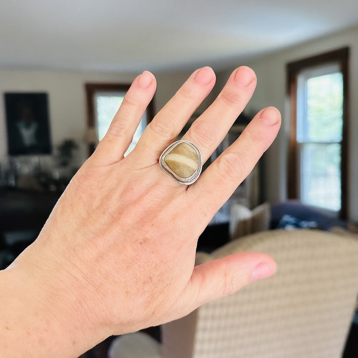 Hand wearing a ring with a stone on a blurred indoor background