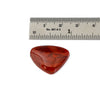 A polished red agate cabochon with natural marbled patterns, shown below a metal ruler for scale on a white background.