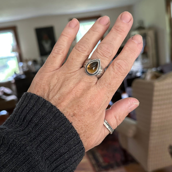 Handmade sterling silver ring  on a hand with high dome teardrop Namibia citrine, sand textured bezel frame and wide textured dome band with oxidized patina, size 9
