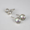 Two pairs of sterling silver earrings with round iridescent coin pearls, displayed on a white surface.