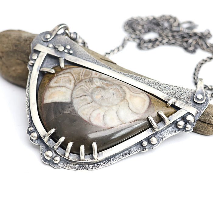 Necklace with a pendant featuring a fossilized ammonite on a white background