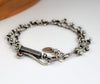 Sterling silver chain bracelet with a citrine in a tube setting, photographed on a white surface with a wooden edge in the corner.