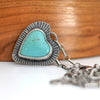 Heart-shaped turquoise stone pendant on a silver chain against a wooden background