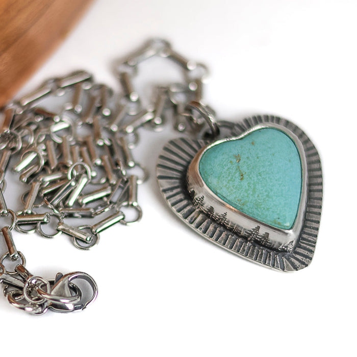 Silver necklace with a heart-shaped turquoise pendant on a white background