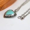 Necklace with a heart-shaped turquoise pendant on a white surface