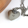 Silver heart-shaped pendant on a chain against a white background