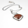 Handmade sterling silver pendant with dark orange rose cut hessonite garnet set point down, sand textured border, on an oval rolo chain