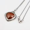Handmade sterling silver pendant with dark orange rose cut hessonite garnet set point down, sand textured border, on an oval rolo chain