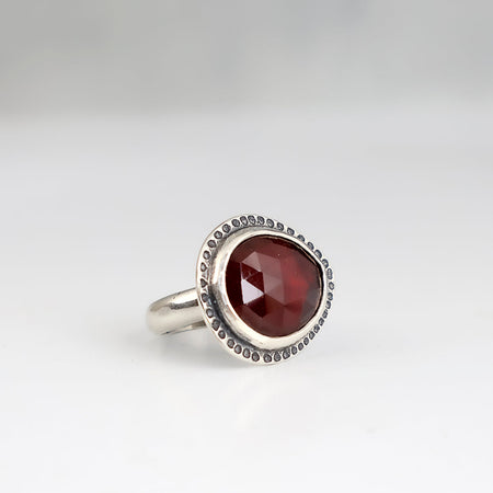 Handmade sterling silver ring with horizontal rose cut hessonite garnet, dot textured bezel border and half round comfort fit band, size 7