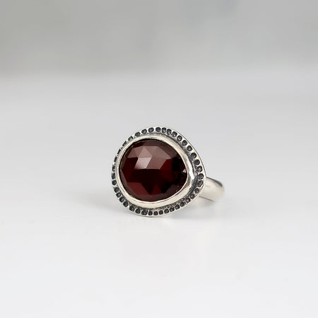 Handmade sterling silver ring with horizontal rose cut hessonite garnet, dot textured bezel border and half round comfort fit band, size 7