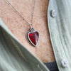 Heart-shaped red pendant necklace on a person wearing a light shirt.