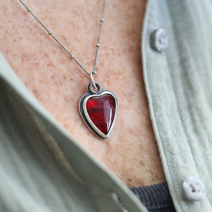 Heart-shaped red pendant necklace on a person wearing a light shirt.