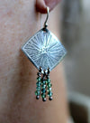 Silver earring with green beads on a person's ear