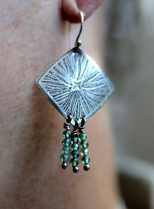 Silver earring with green beads on a person's ear
