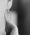 Silver hoop earring on a blurred background