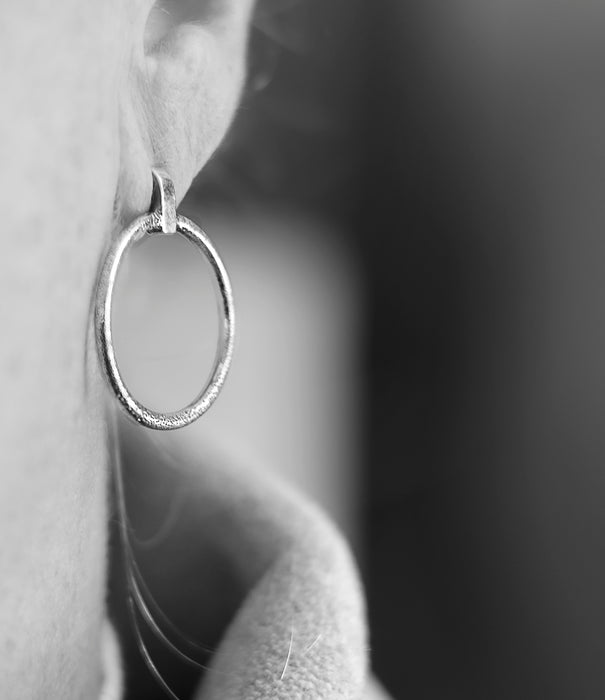 Silver hoop earring on a blurred background