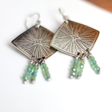 Silver earrings with green apatite beads on a white background
