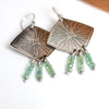 Silver earrings with green apatite beads on a white background