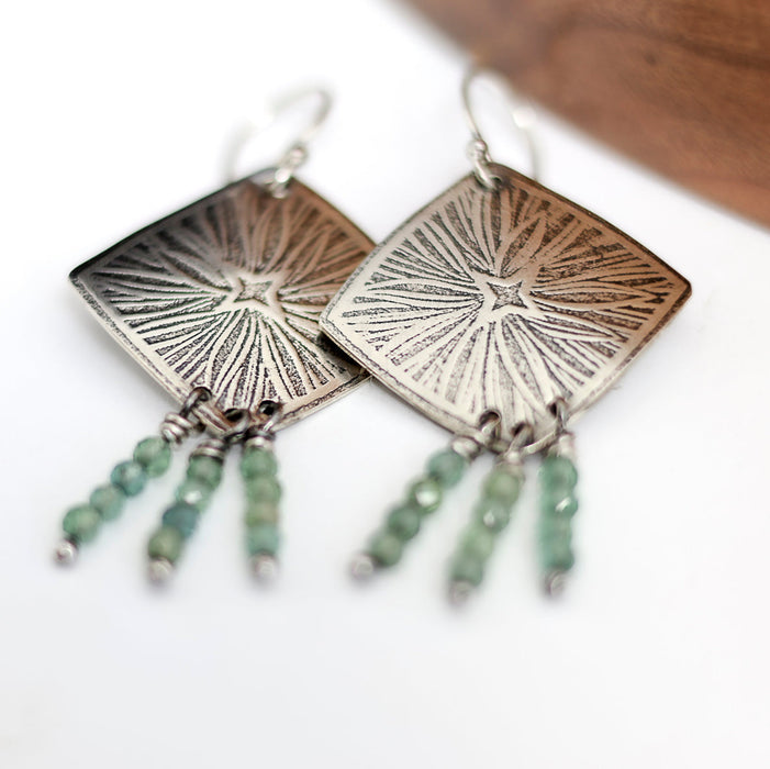 Pair of silver earrings with green beads on a white background