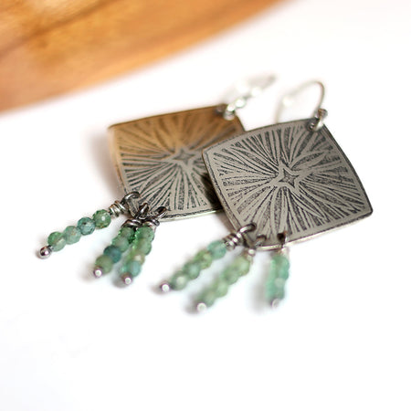 Pair of silver earrings with green beads on a white background
